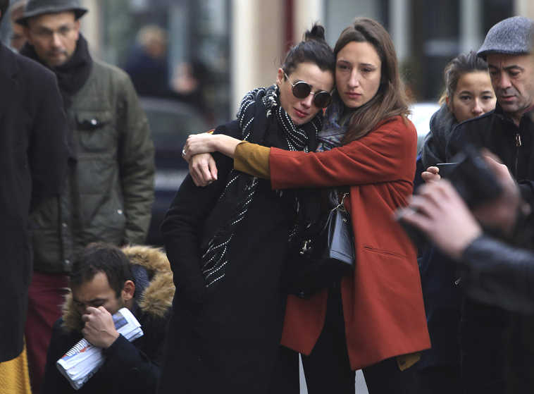 Women comfort each other as they stand in front of the Carillon cafe, in Paris, Saturday, Nov.14, 2015. French President Francois Hollande vowed to attack Islamic State without mercy as the jihadist group admitted responsibility Saturday for orchestrating the deadliest attacks inflicted on France since World War II. (AP Photo/Thibault Camus)