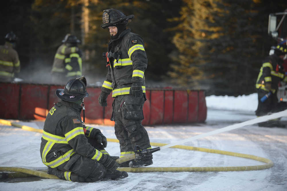 Photo by Megan Pacer/Peninsula Clarion Jason Cooper, left, and Dan Jensen, right, check in with each other during a practice drill on Tuesday, Nov. 17, 2015 at the Central Emergency Services station on Kalifornsky Beach Road. The firefighters have been training for about two months for an upcoming engineering test.
