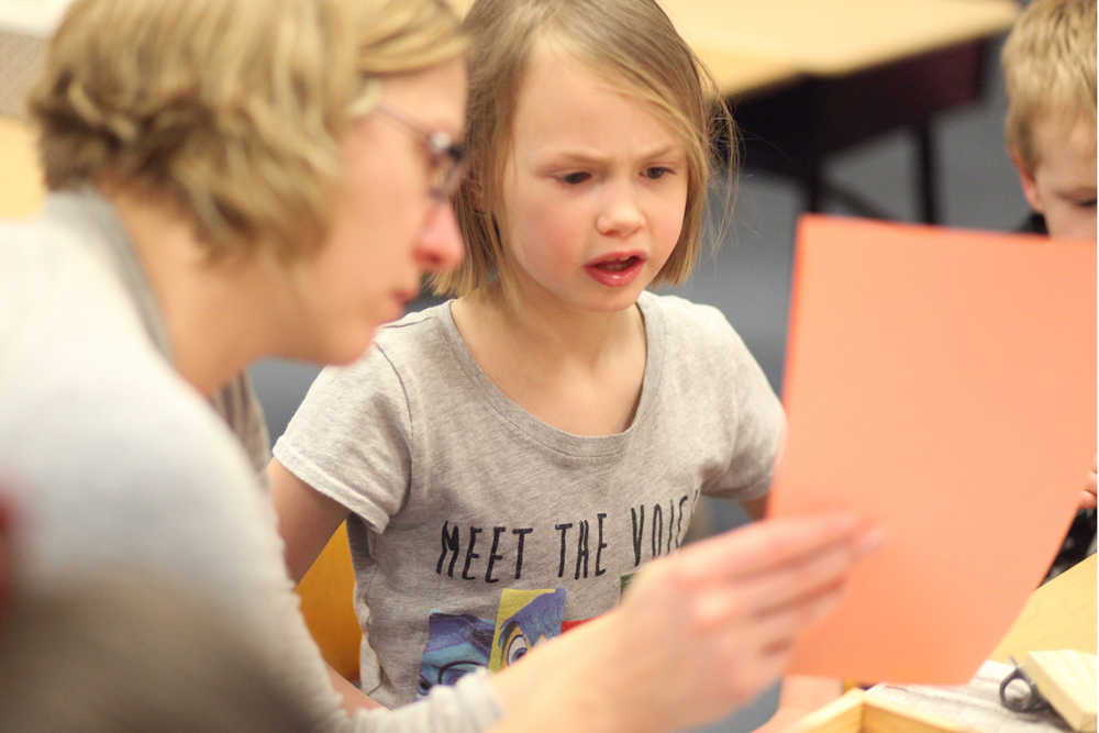 Photo by Kelly Sullivan/ Peninsula Clarion (Left) Danya Olson holds the building instructions up for her daughter, second grader Aeroh Olson, to read out loud Thursday, Dec. 3, 2015, at Mountain View Elementary School in Kenai, Alaska.