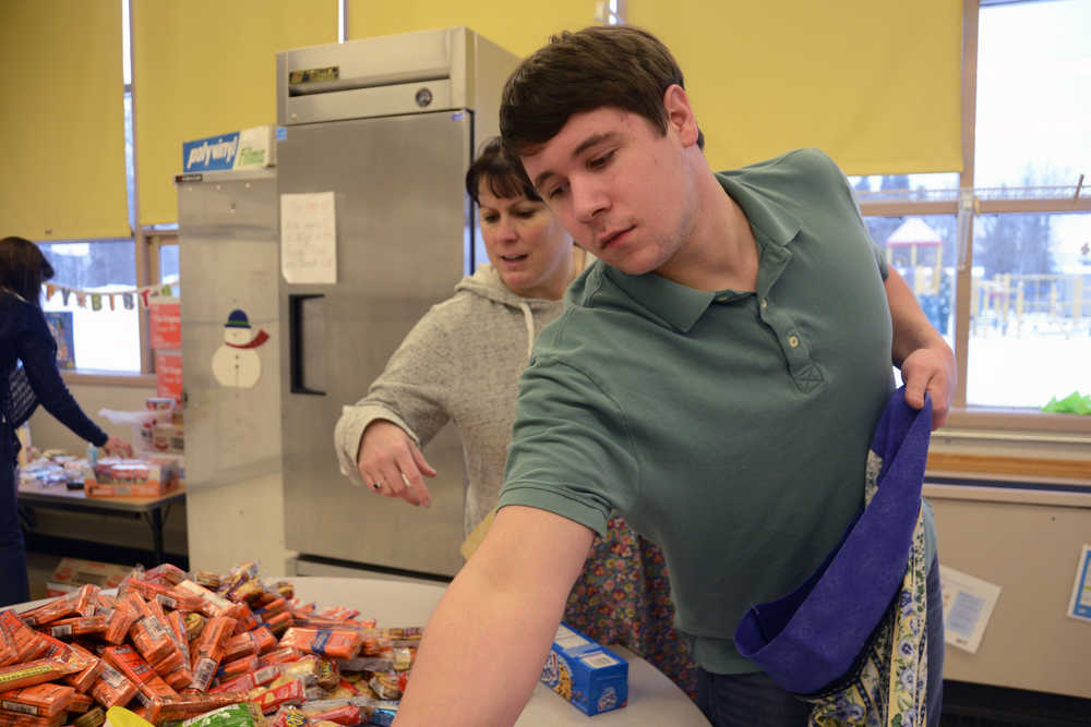 Photo by Megan Pacer/Peninsula Clarion Jacob Dye, right, and his mother, Jennifer Dye, fill hand-made pillow cases with snacks and other presents on Monday, Dec. 14, 2015 at Kenai Alternative High School in Kenai, Alaska. They joined other volunteers filling the 66 cases, which will be presented to youth during this year's "Grinch Day" celebration later this week. The snacks were donated by the Soldotna United Methodist Church, the Our Lady of Angels Catholic Church and the River Covenant Church.