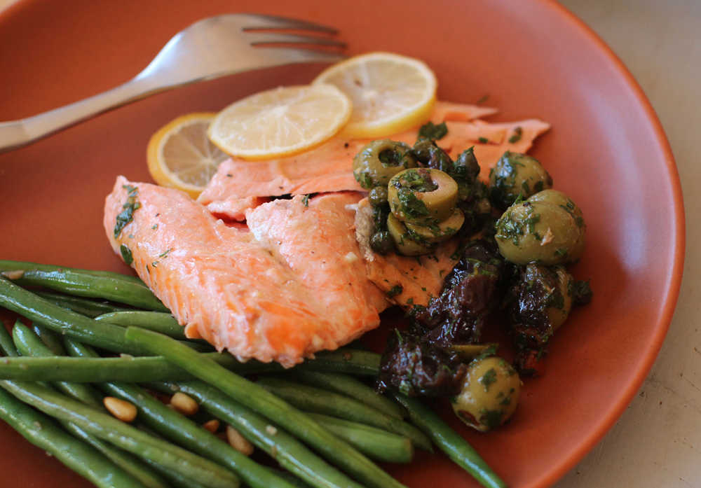 This Nov. 9, 2015 photo shows roasted salmon with lemons, prunes and olives in Concord, NH. It makes for a pretty dramatic and colorful holiday meal centerpiece. Plus, roasted salmon is incredibly easy, quick (taking minutes, not hours like many roasts), and is versatile. (AP Photo/Matthew Mead)