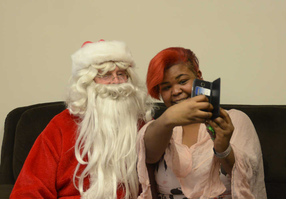Photo by Megan Pacer/Peninsula Clarion Kenai Alternative High School senior Linda Byrd takes a picture with Hal Smalley, posing as Santa Clause, during the annual Grinch Day celebration on Thursday, Dec. 17, 2015 at the school in Kenai, Alaska. Byrd also celebrated her 19th birthday during the annual lunch and gift-giving event.