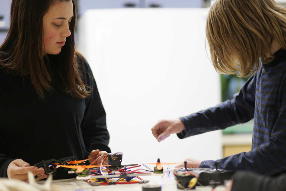 Photo by Kelly Sullivan/ Peninsula Clarion Seventh grader Brady Evoy shows eleventh grader Ceyara Showalter a few things about small drones, Wednesday, Dec. 9, 2015, at Nikiski Middle-High School in Nikiski, Alaska. Showalter recently joined the program and is still getting caught up, she said.
