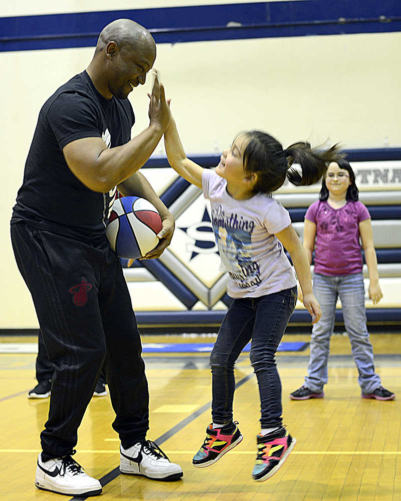 Photo by Rashah McChesney/Peninsula Clarion Former Harlem All Star Les "Pee-Wee" Harrison, gets a high-five from Savannah Prieto, 5, after he helped her perform a trick during a presentation on Monday Dec. 21, 2015 in Soldotna, Alaska.