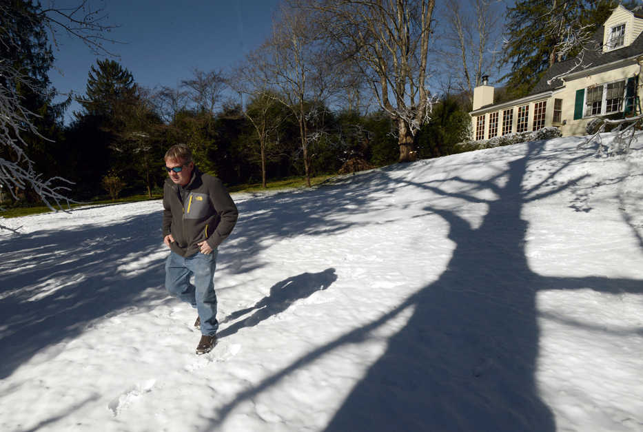 In this Jan. 5, 2016 photo, Blair Bullock walks by his home after he used a homemade snow machine to cover his front yard with snow, in Bristol, Va. The snow, which began "falling" Monday night and continued into Tuesday morning, is the manmade variety thanks to a snow gun - a combination of pipe, valves and an oscillating electric motor - engineered and built by Bullock. (David Crigger/The Bristol Herald-Courier via AP) MANDATORY CREDIT
