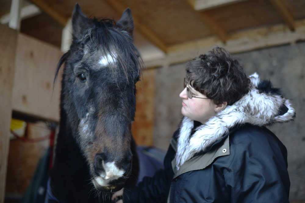Ben Boettger/Peninsula Clarion Cristal Barton touches the shoulder of her horse Major on Thursday, Jan. 7 at the home of Barton's mother, Kim Garrettson, in Kenai. The Kenai City Council announced Thursday that Garrettson will be allowed to keep Major in Kenai in exception to city code, a permission previously denied by Kenai's Planning and Zoning Commission.