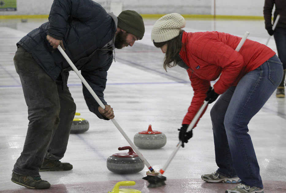 In this Jan. 2 photo, Rich Savoyski, left, and Kara Zwickey furiously sweep in front of their teams' curling stone to bring it into the red-outlined house to score a goal at Kevin Bell Arena in Homer.(Anna Frost/The Homer News)