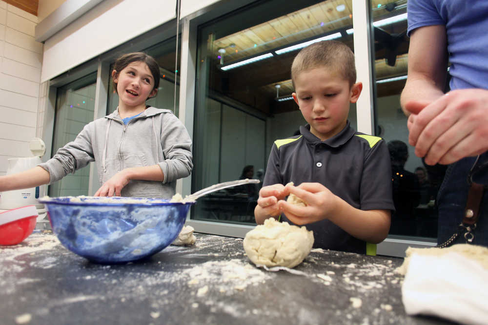 Photo by Megan Pacer/Peninsula Clarion Emaline Cruickshank, left, helps her younger brother, Tyler Cruickshank, prepare balls of corn flour dough to be made into fresh tortillas during a workshop on Thursday, Jan. 14, 2016 at the Kenai Community Library in Kenai, Alaska.