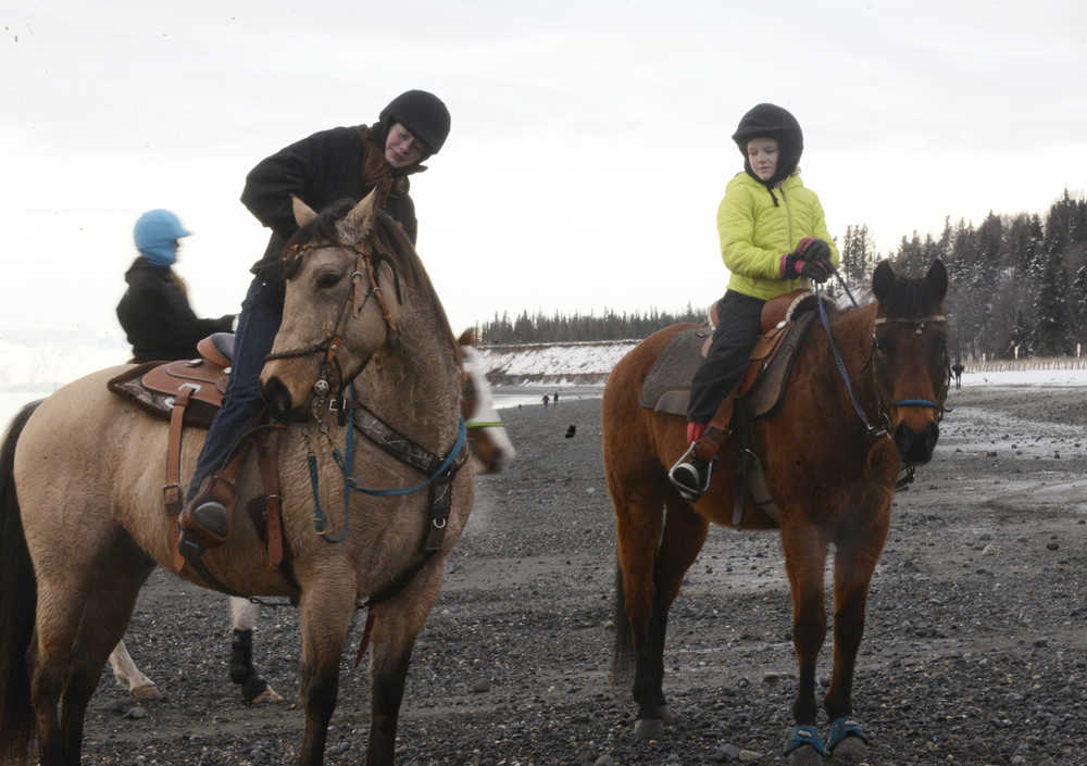 Photo by Megan Pacer/Peninsula Clarion Soldotna resident Madelyn Barkman, left, and Kenai resident Mercedes Tapley, right, ride along the beach with other members of the Alaska C & C Horse Adventures group on Monday, Jan. 18, 2016 in Kenai, Alaska.