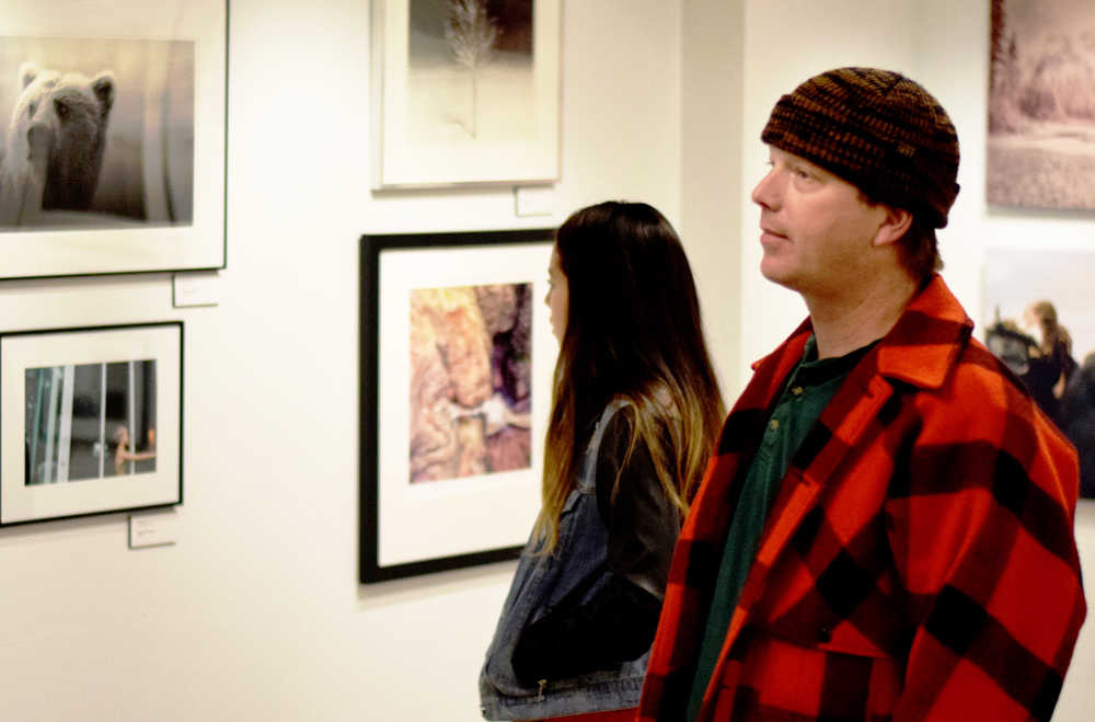 Ben Boettger/Peninsula Clarion Greg Hicks (in plaid) examines an image at the opening reception of the Rarified Light photography exhibit on Thursday, Jan. 14 at the Kenai Fine Arts Center.