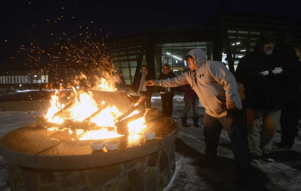 Photo by Megan Pacer/Peninsula Clarion Soldotna resident Abraham Anasogak throws a plant offering into the flames of a Raven Fire Circle during a healing gathering called "You and Me" on Wednesday, Jan. 20, 2016 at the Dena'ina Wellness Center in Kenai, Alaska. The gatherings are held periodically to support those affected by suicide or death, and have lavender, sage and sweetgrass available for participants to burn in the healing process.