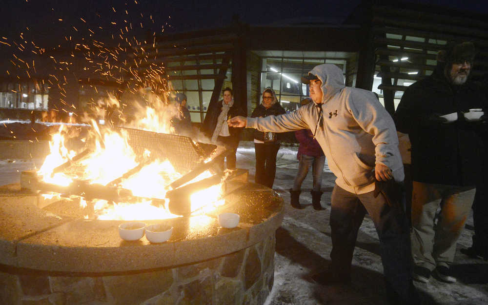 Photo by Megan Pacer/Peninsula Clarion Soldotna resident Abraham Anasogak throws a plant offering into the flames of a Raven Fire Circle during a healing gathering called "You and Me" on Wednesday, Jan. 20, 2016 at the Dena'ina Wellness Center in Kenai, Alaska. The gatherings are held periodically to support those affected by suicide or death, and have lavender, sage and sweetgrass available for participants to burn in the healing process.