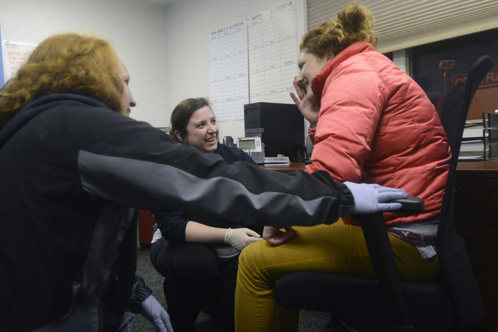 Photo by Megan Pacer/Peninsula Clarion Holly Behrens, left, and Amanda Dorough, center, attend to Jessica Roper, right, while she poses as a patient during an emergency response drill on Tuesday, Jan. 19, 2016 at the Central Emergency Services Station 4 on Kalifornski-Beach Road near Kenai, Alaska. CES hosts drill nights each Tueasday so full-time staff and members of the volunteer program can stay up to date on their training.