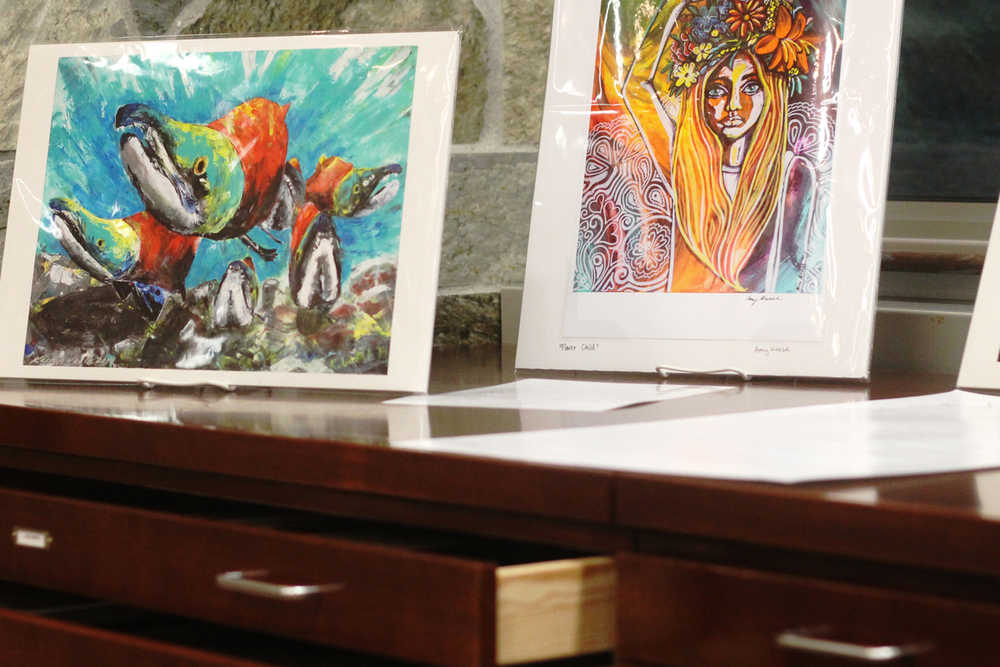 Ben Boettger/Peninsula Clarion Prints by Kaitlin Vadla (left, with salmon), Amy Kruse, and Susan Biggs sit on top a set of drawers exhibiting work by 10 local artists at the Soldotna Public Library on Monday, Feb.1 in Soldotna.