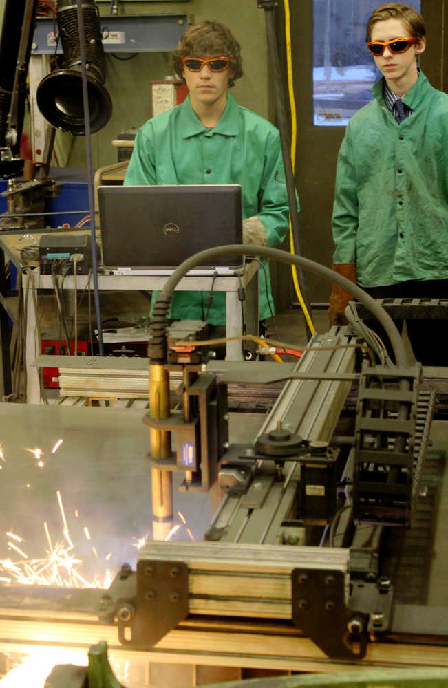 Ben Boettger/Peninsula Clarion Kenai Central High School freshmen Damien Redder (left) and Jude Gabriel use a plasma cutter to slice out a "K" for a Kenai sign on Wednesday, Feb. 3 at Kenai Central High School.