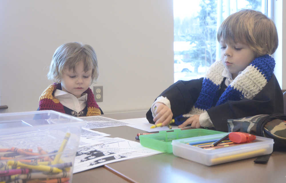 Photo by Megan Pacer/Peninsula Clarion Temperance Taylor, 3, and her 5-year-old brother, Westley Taylor, color in drawings in their handmade robes and scarves during Harry Potter Book Night on Thursday, Feb. 4, 2016 at the Soldotna Public Library in Soldotna, Alaska.