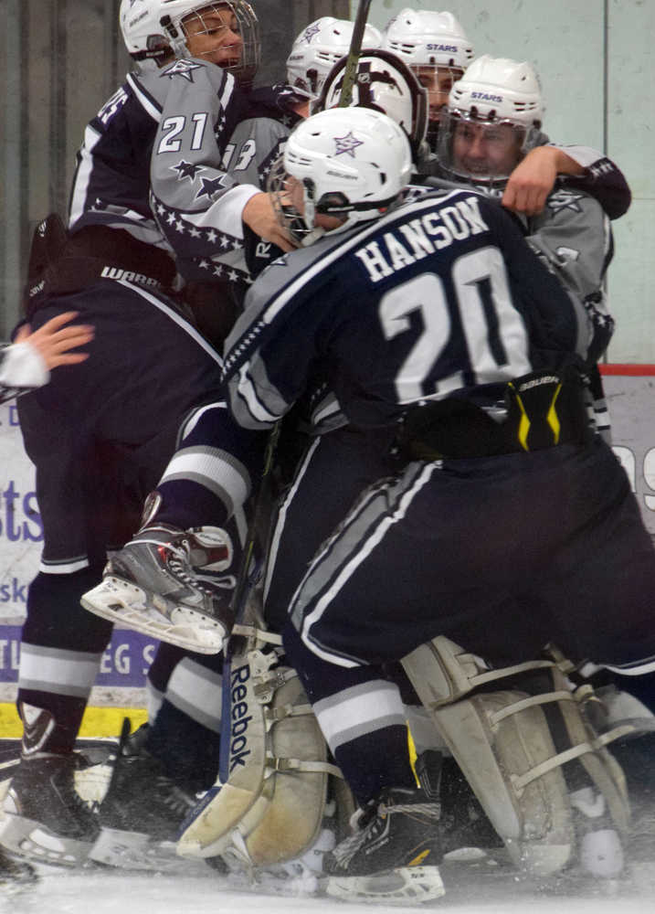 Photo by Jeff Helminiak/Peninsula Clarion Trevor Witthus (21) and Corey Hanson (20) help teammates mob goalie Billy Yoder after the Soldotna hockey team defeated Palmer 3-1 on Friday at the North Star Conference  hockey tournament at the Soldotna Regional Sports Complex to earn a state berth.