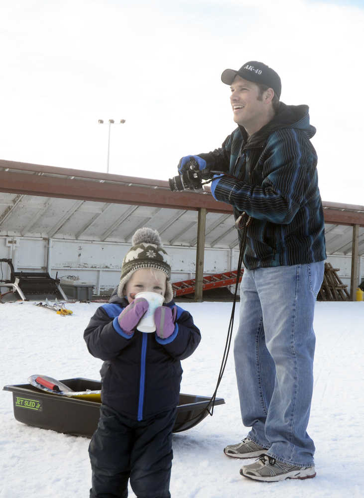 Photo by Megan Pacer/Peninsula Clarion Soldotna resident Jason Sulley and his son, 2-year-old Corbin, look on as Jason's wofe, Angie, collects a prize during the Women's Stud Run on Sunday, Feb. 7, 2016 at the Tsalteshi Trails in Soldotna, Alaska. Formerly the Ski for Women, the Stud Run allowed participants to ski, run or snowshoe the 5K trail.