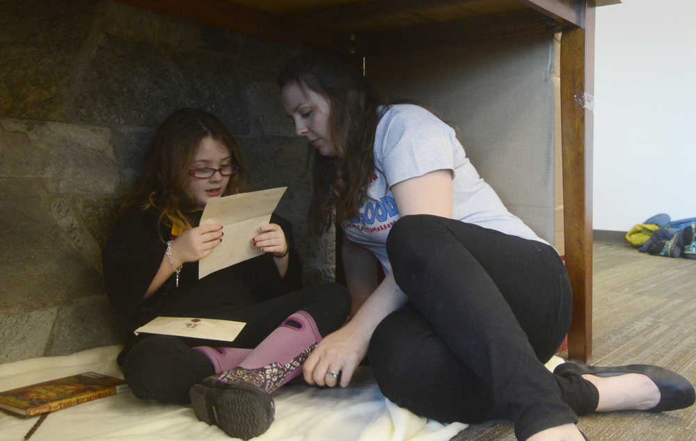 Photo by Megan Pacer/Peninsula Clarion Mariah Ross and her 6-year-old daughter, Adelynn, read tucked away in a makeshift "cupboard under the stairs" during Harry Potter Book Night on Thursday, Feb. 4, 2016 at the Soldotna Public Library in Soldotna, Alaska.