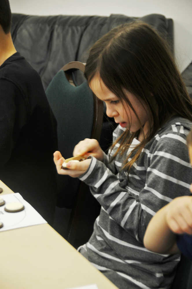 Photo by Elizabeth Earl/Peninsula Clarion Morgan Carlson-Kelly, 7, carefully cuts the frosting on her Oreo "moon" at the Kenai Challenger Center on Tuesday. Carlson-Kelly participated in the STEAM Ahead Homeschool program at the Challenger Center, where homeschool students can enroll to learn about science.