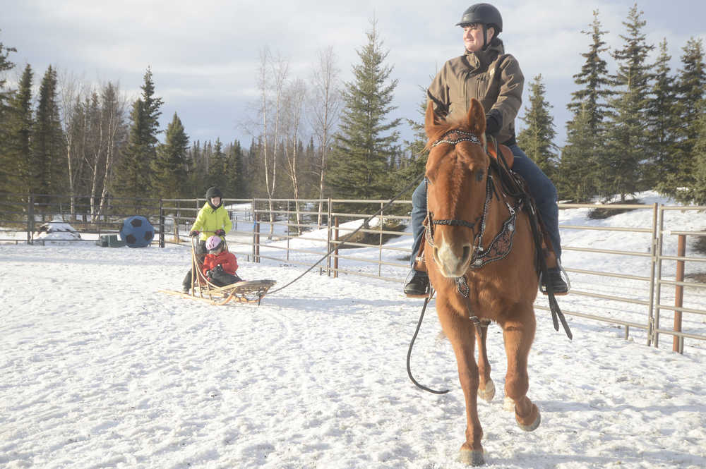 Photo by Megan Pacer/Peninsula Clarion Connie Green and her horse, Sequoia, pull 11-year-old Mercedes Tapley and 8-year-old Sophie Tapley around an enclosure on a sled on Monday, Feb. 8, 2016 at Alaska C&C Horse Adventures In Soldotna, Alaska.