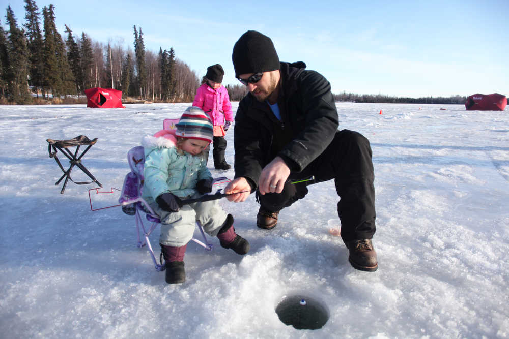 Evan Frisk helps 3-year-old Behati Frisk prepare her pole for ice fishing during an outing on Wednesday, Feb. 17, 2016 at Sport Lake in Soldotna, Alaska. Hundreds of students from several Kenai Peninsula schools and home-school programs got try their hand at ice fishing during the 17th annual multiple-day event, which is part of the Salmon in the Classroom program hosted by the Alaska Department of Fish and Game Division of Sport Fish.