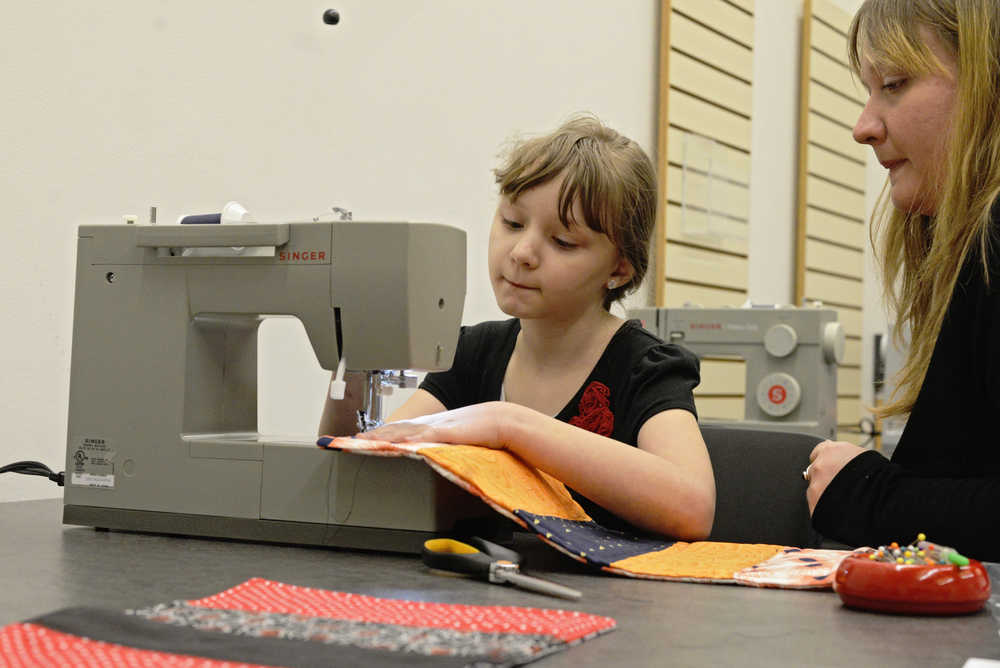 Clara Cozzini sews a quilt for a doll with help from librarian Ryanna Thurman at a meeting of the "All Dolled Up" club on Saturday Feb. 20 at the Kenai Public Library. The free group meets monthly at the Kenai Community Library to craft doll accessories and play. On Saturday they sowed quilts and made lunchboxes from Altoid tins; in March they will sow scarves.