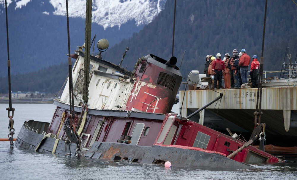 Crew aboard the barge-crane Brightwater lifts the sunken 96-foot tugboat Challenger in Gastineau Channel on Sunday. Once the tug is dewatered, patched and stabilized, the WWII era vessel will be towed to the AJ Cruise Ship Dock for further work.