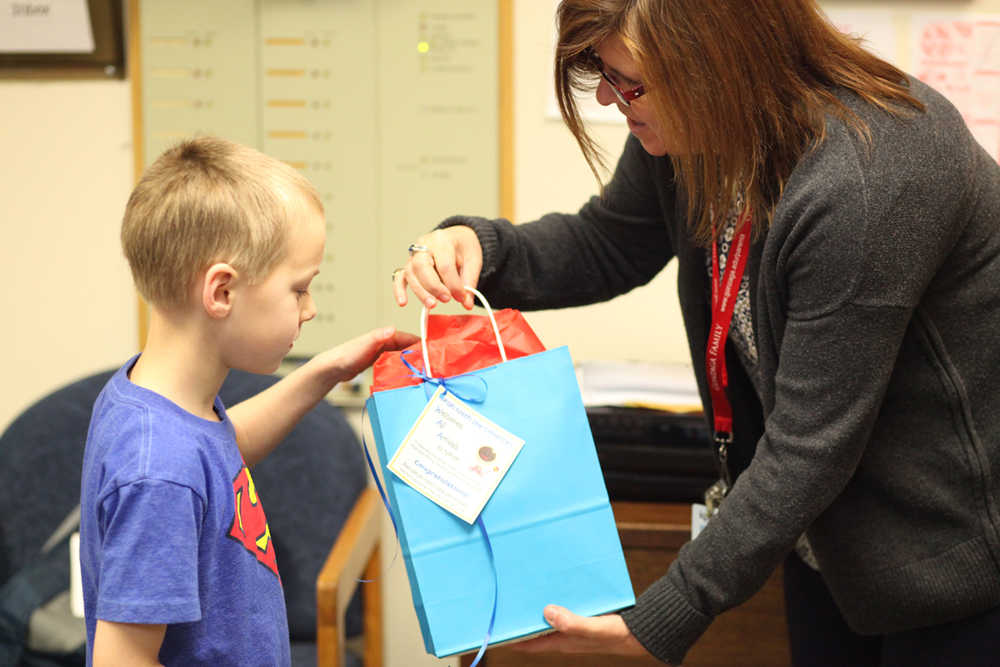 Photo by Kelly Sullivan/ Peninsula Clarion Principal Margaret Gilman hands first grader Regan Savly one of the Baby Baskets that staff and students put together to welcome the newest additions to the Nikiski North Star Elementary School community Wednesday, Feb. 24, 2016, at the school in Nikiski, Alaska.