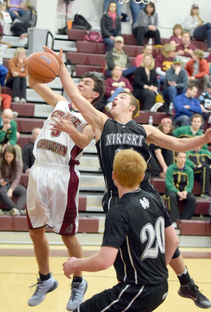 Photo by Joey Klecka/Peninsula Clarion Nikiski senior Nathan Carstens (center) attempts to swat away a rebound from Grace guard Nate Salima (left) in Friday's semifinal contest at the Southcentral Conference tournament at Grace Christian High.