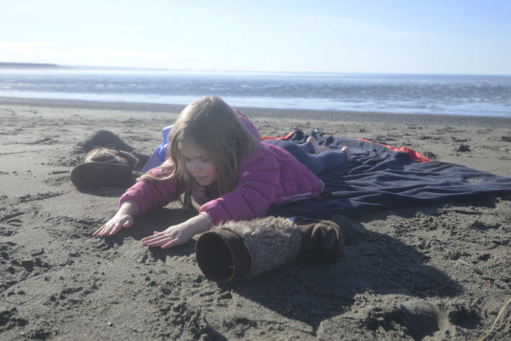 Isla Nelson, 5, plays in the sand while her mother, Soldotna resident Betty Nelson, and grandmother, Juneau resident Sue Carlson, enjoy a sunny day at the beach on Sunday, March 13, 2016 at the mouth of the Kenai River in Kenai, Alaska.
