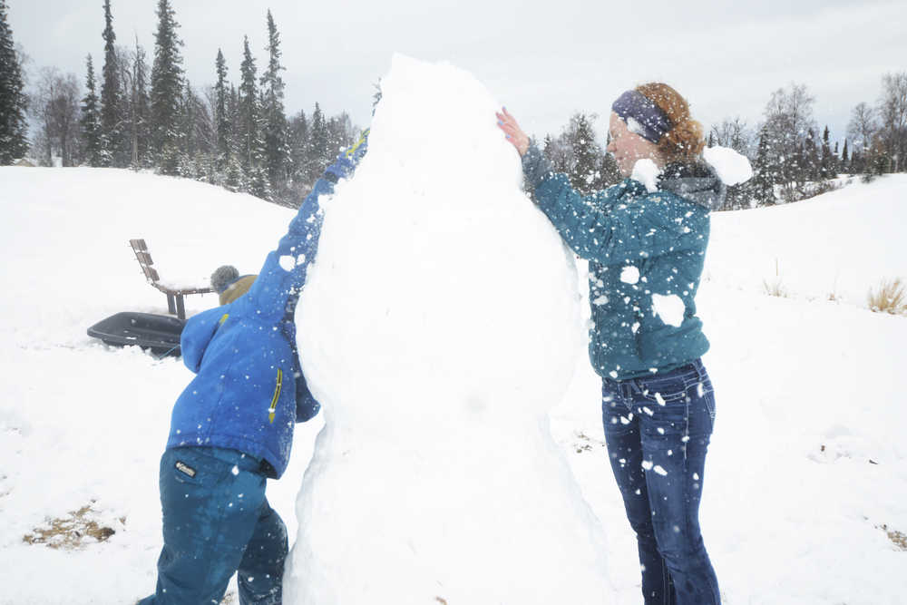 Dmitry Marlowe, 9, and Lydia Marlowe, 14, put the finishing touches on a snowman on Sunday, March 20, 2016 at the Kenai Golf Course in Kenai, Alaska. The first day of Spring found Kenai coated in a layer of wet, sticky snow after several days of sunshine.