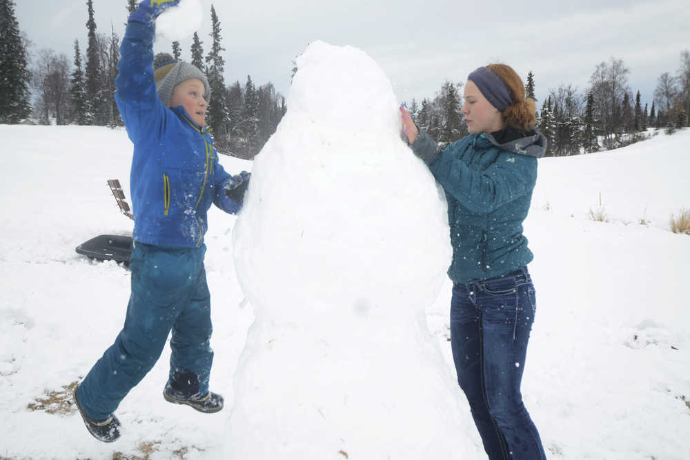 Dmitry Marlowe, 9, and Lydia Marlowe, 14, put the finishing touches on a snowman on Sunday, March 20, 2016 at the Kenai Golf Course in Kenai, Alaska. The first day of Spring found Kenai coated in a layer of wet, sticky snow after several days of sunshine.