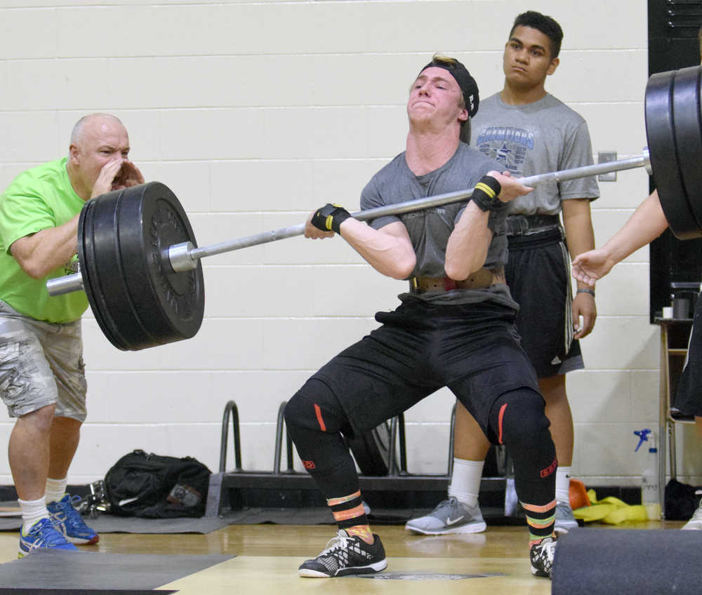 Photo by Jeff Helminiak/Peninsula Clarion Sophomore Rykker Riddall sets the record in the Freshmen/Sophomore Clean on Wednesday in the Speed and Strength Training competition. At left, yelling encouragement, is Riddall's father, Ted Riddall.