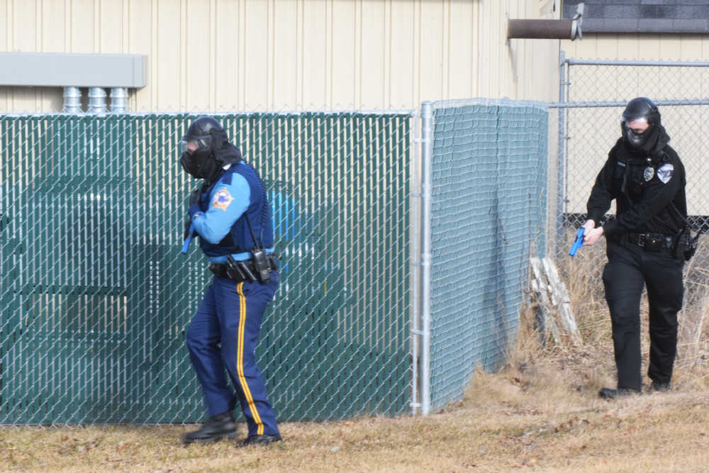 Photo by Megan Pacer/Peninsula Clarion An Alaska State Trooper and a Soldotna Police officer round a fence in preparation to pursue a simulated active shooter during an Alaska Shield exercise on Thursday, March 31, 2016 at the Kenai Peninsula Borough building in Soldotna, Alaska.
