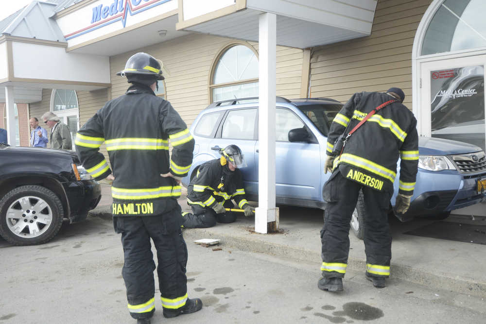 Photo by Megan Pacer/Peninsula Clarion Members of the Kenai Fire Department knock pillars back into place after a driver backed onto the pavement and struck the MediCenter building on Monday, April 11, 2016 in Kenai, Alaska.