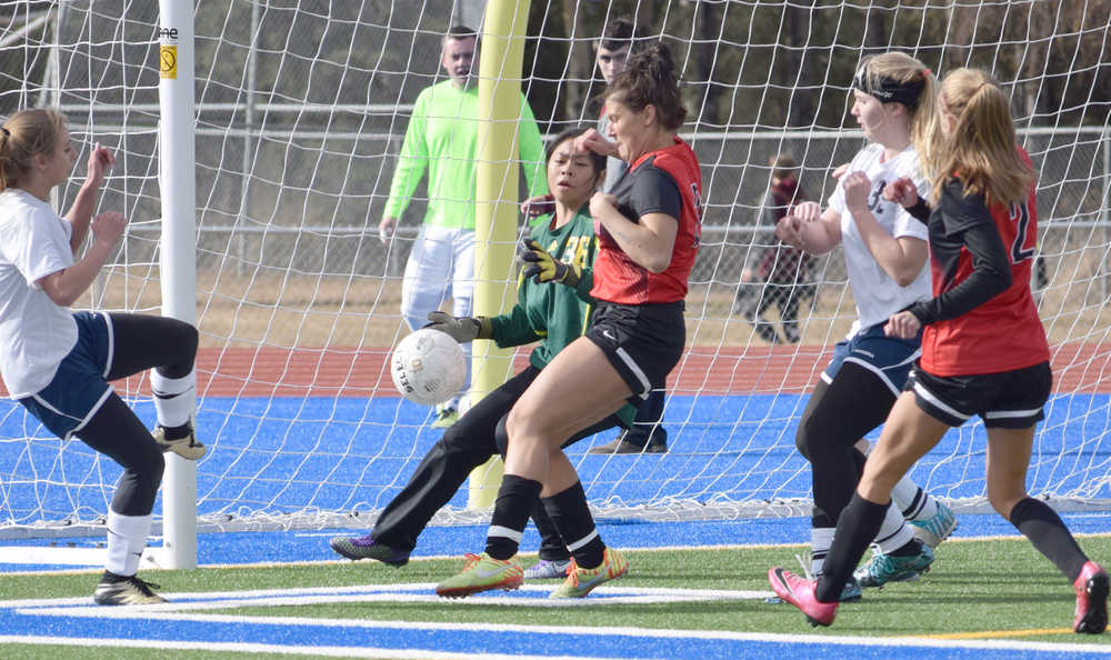 Photo by Jeff Helminiak/Peninsula Clarion Kenai Central's Sarah Every (center) tries to strike the ball in front of Marlayna Saavedra before the ball rolls just wide of the goal Thursday at Soldtona High School.