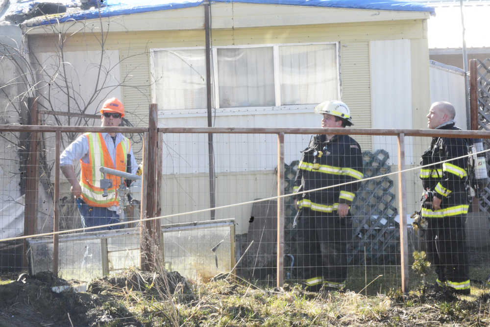 Members of the Kenai Fire Department and Enstar Natural Gas Co. finish putting out a shed fire Thursday, April 21, 2016 on North Dogwood Road in Kenai. The fire, which took about a half hour to extinguish, burnt two sheds, a chicken coop and the outside of a home, but harmed no one.