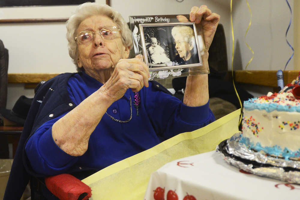Photo by Megan Pacer/Peninsula Clarion Hazel George opens a present - side-by-side photos of her as a baby and in the present - during a birthday party Sunday, April 24, 2016 at Heritage Place in Soldotna, Alaska. George joined the other centenarians in the state when she turned 100 Sunday.