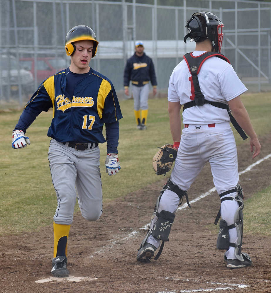 Photo by Joey Klecka/Peninsula Clarion Homer's Kyle Johnson (17) tags home plate to score a run behind Kenai Central catcher Taylor Landry Tuesday evening at the Kenai Little League Fields.