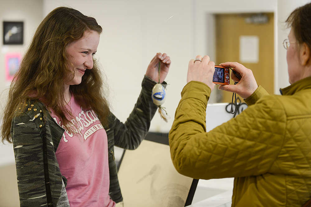 Matthea Boatright, 14, poses with her entry into the PEEPs art show for the Kenai Peninsula Birding Festival as her mother, Kirsten Boatright, takes her picture on Thursday May 7, 2015 at the Kenai Fine Arts Center in Kenai, Alaska. The birding festival kicks off Thursday. (Clarion file photo)