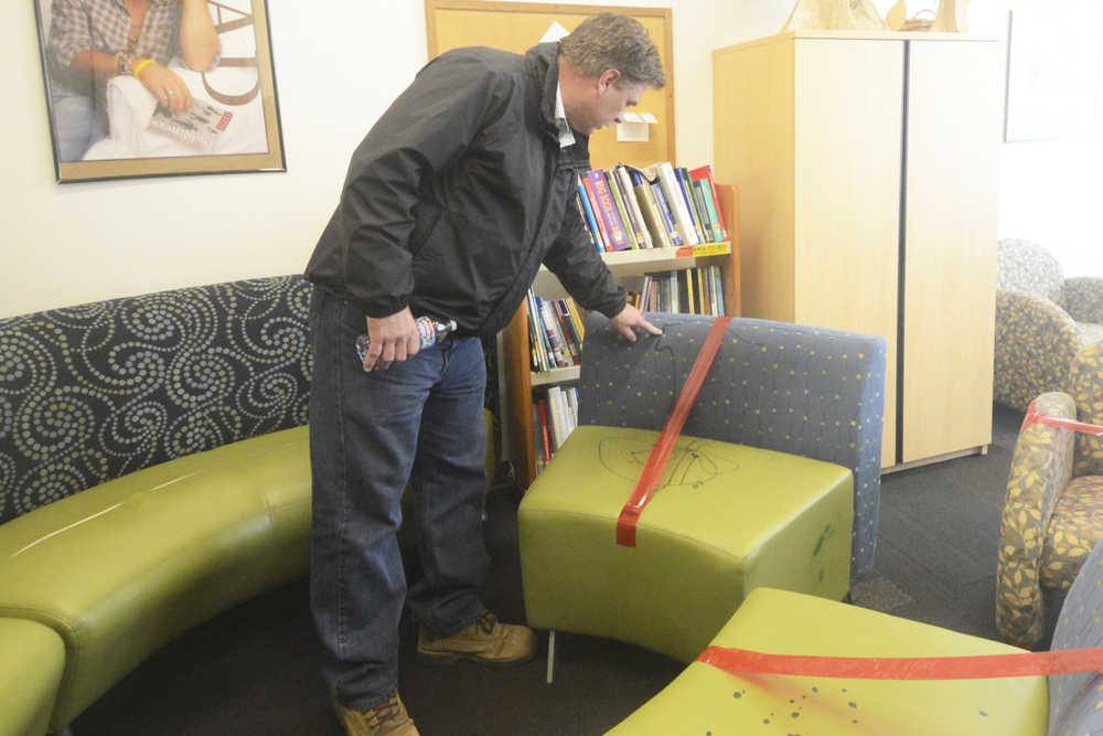 Photo by Megan Pacer/Peninsula Clarion Kenai Vice Mayor Brian Gabriel inspects a vandalized piece of furniture Wednesday, May 25, 2016 at the Kenai Community Library in Kenai, Alaska. Several chairs and a stool were destroyed with a paint-like substance, and a couch was slashed with a knife at the library last week.