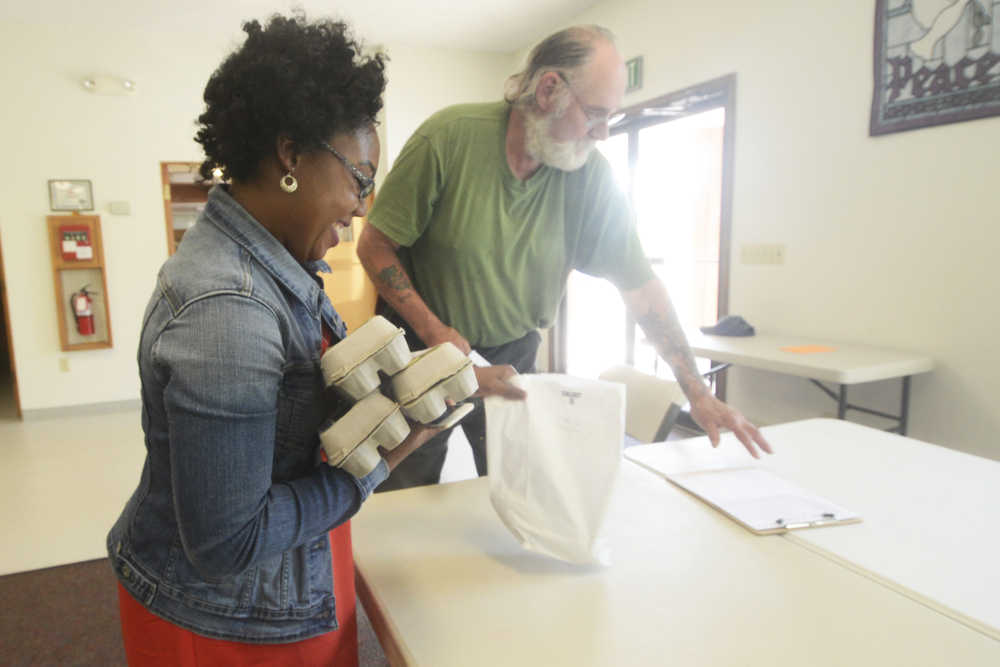 Photo by Megan Pacer/Peninsula Clarion Kenai resident Brie Havrilla picks up eggs and cucumbers from Steve Dahl through the Kenai Peninsula Food Hub on Tuesday, June 7, 2016 at Christ Lutheran Church in Soldotna, Alaska. Through the pilot program, which launched in May, customers can place online orders for locally made produce and goods and pick them up on certain days in Soldotna and Homer.