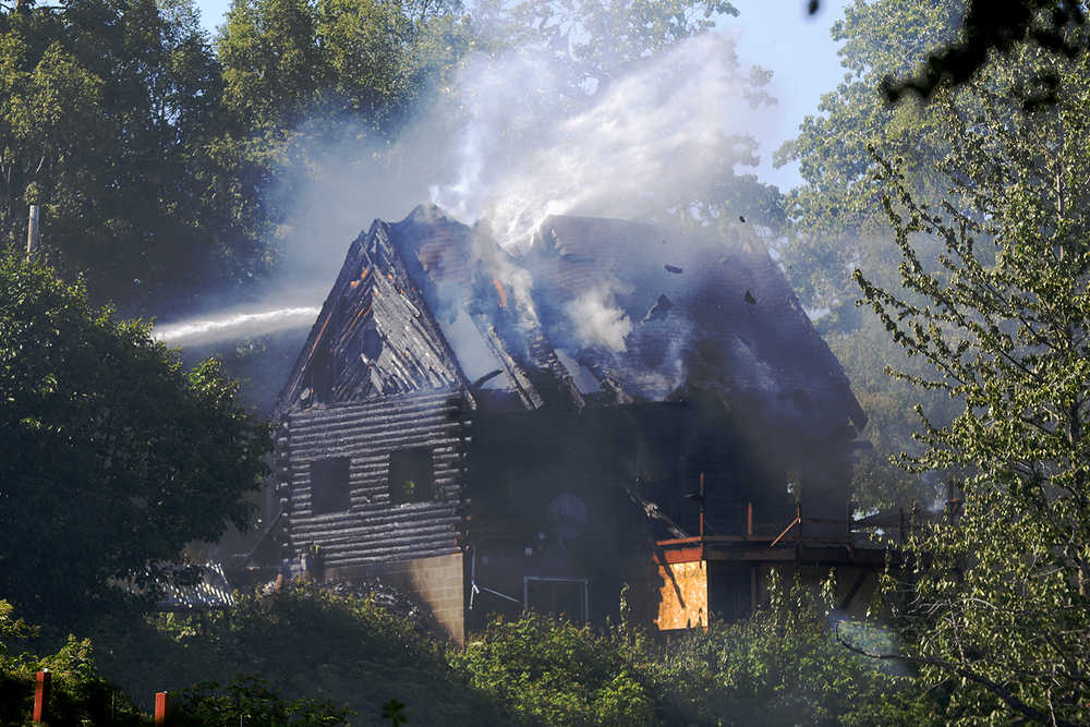 Ben Boettger/Peninsula Clarion A stream of water from a Nikiski fire engine dowses the remains of a burnt cabin in the McGahan Ridge neighborhood on Wednesday, June 8 in Nikiski.. The cabin was unoccupied at the time of the fire and there were no injuries.
