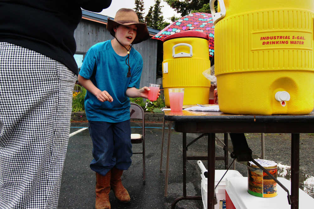 Michael Dominic pours two glasses of pink lemonade for a customer at his stand outside Charlotte's Cafe on Saturday, June 11 in Kenai.