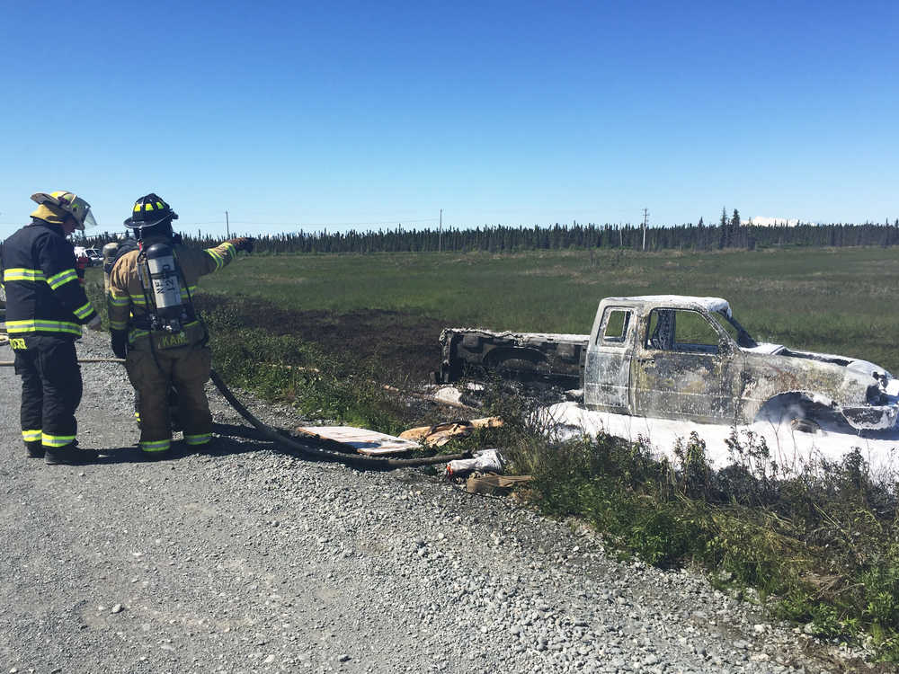 Photo by Megan Pacer/Peninsula Clarion Firefighters finish up work on a vehicle that rolled over and caught fire Wednesday, June 15, 2016 on Marathon Road between Nikiski and Kenai. The burning vehicle caught a small area of grass of fire, which was also put out.