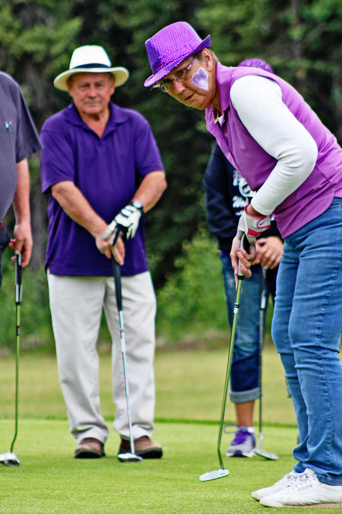 Buttons Bush putts her golf-ball into a hole at the Alzheimer's Association's Longest Day golf tournament fundraiser on Saturday, June 18 at the Bird Homestead golf course in Funny River. Her teammates looking on are Keith Stewart (left), husband Bob Bush, and daughter Karen Burger. Bush's team - one of the nine competing - wore purple, the Alzheimer's Association's awareness color. Burger, an organizer, said that the tournament had raised $1,900 for Alzheimer's disease research before its conclusion Saturday night.