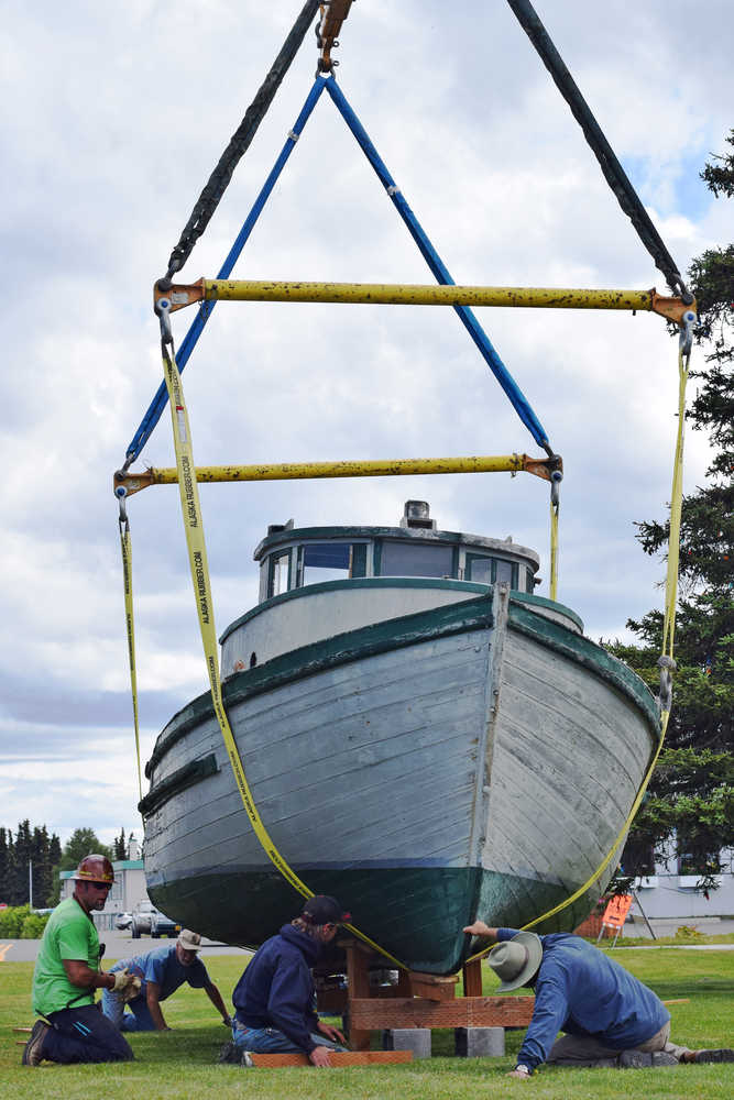 Ben Boettger/Peninsula Clarion Using a crane from Peak Oilfield Services, volunteers for the Kenai Historical Society help place a wooden fishing boat, built in 1929, on struts in front of the Kenai Visitors Center on Wed. June 19, 2016 in Kenai, Alaska.  The boat, donated by Dave and Linda Hutchings, will be kept there as a historical exhibit.