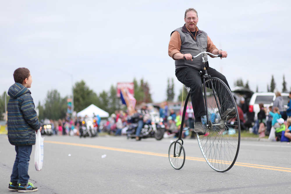 Photo by Kelly Sullivan/ Peninsula Clarion Doug Field hopped on and off his Penny Farthing during Kenai's July 4th Parade to demonstrate how to ride the tall bicycle Monday, July 4, 2016 in Kenai, Alaska.