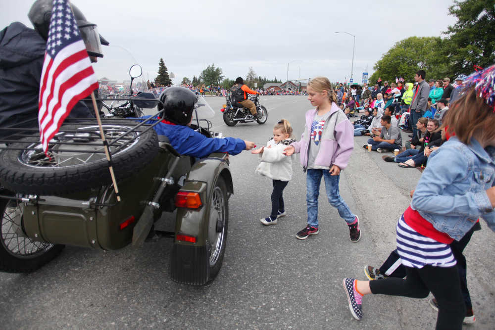 Photo by Kelly Sullivan/ Peninsula Clarion Kristin Freed and Addyon Carr rush to grab a handful of candy during Kenai's July 4th Parade on Monday, July 4, 2016 in Kenai, Alaska.